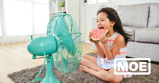 A young girl sitting in front of a fan on a hot day.
