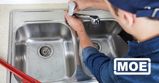 A plumber fixing a kitchen faucet.