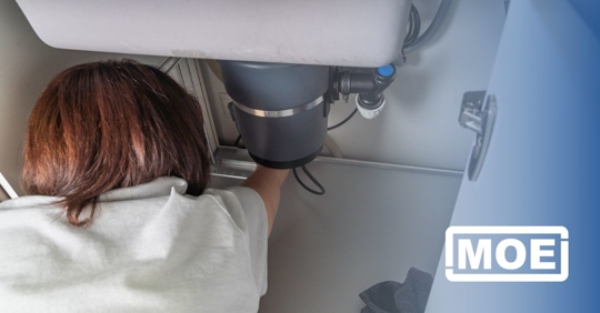 Woman looking under sink.