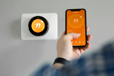 A homeowner adjusting their thermostat through a smartphone