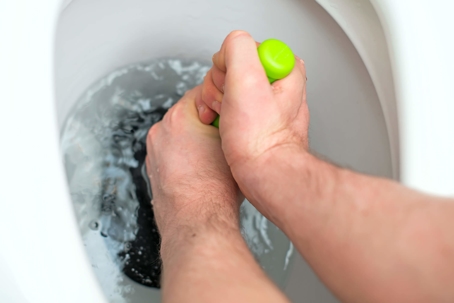 Person attempting to unclog their toilet using a plunger